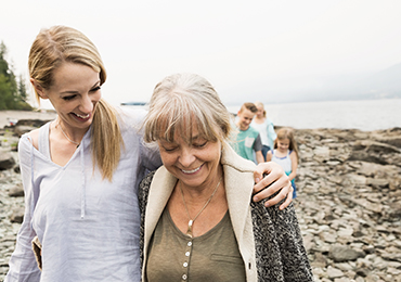 Mother with adult child walking by the lake during autumn 